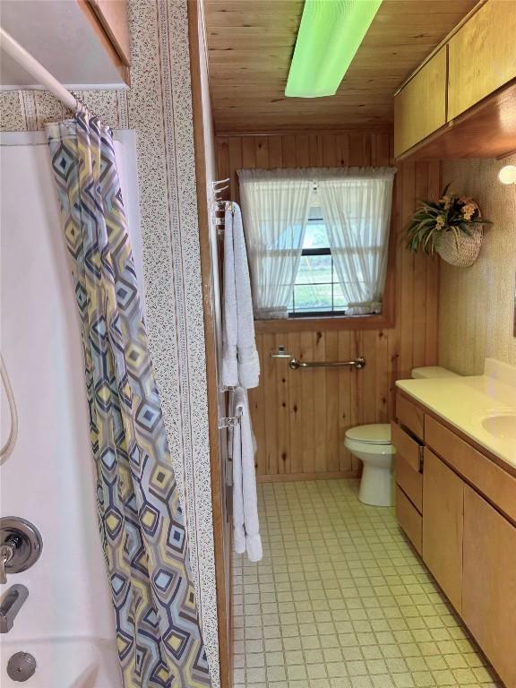 full bathroom featuring wooden walls, toilet, wooden ceiling, and vanity