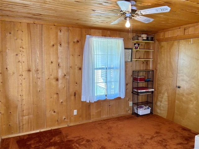 empty room with carpet flooring, wooden walls, wood ceiling, and ceiling fan