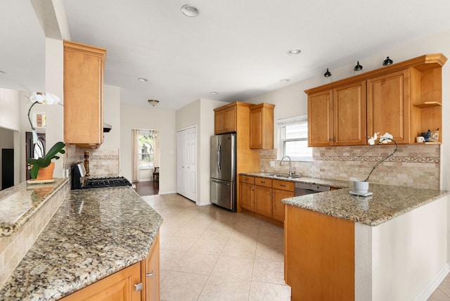 12528 E Labrador Cv, Austin, TX 78729 - kitchen featuring stainless steel appliances, a peninsula, tasteful backsplash, light stone countertops, and light tile patterned flooring