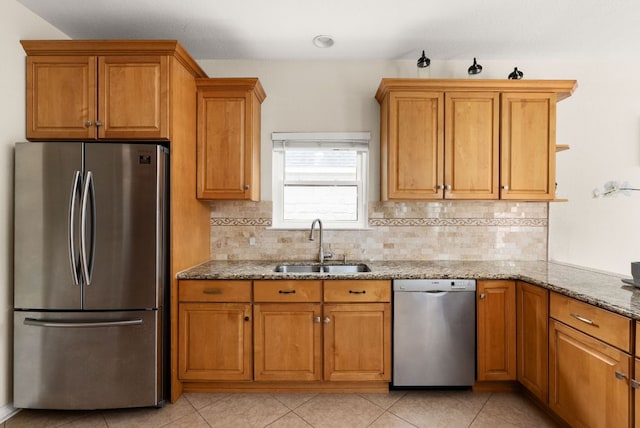 12528 E Labrador Cv, Austin, TX 78729 - kitchen with appliances with stainless steel finishes, light stone counters, decorative backsplash, brown cabinetry, and light tile patterned flooring