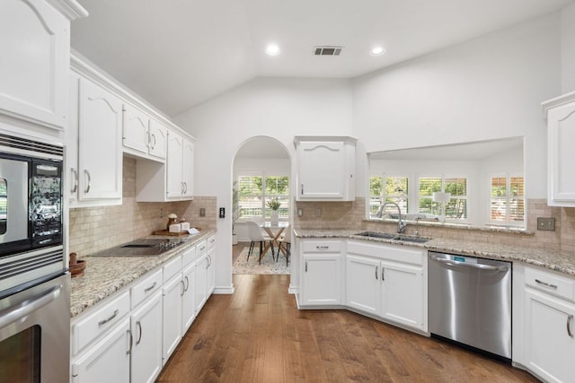 30203 Hacienda Ln, Georgetown, TX 78628 - kitchen with appliances with stainless steel finishes, lofted ceiling, white cabinets, decorative backsplash, and dark wood-style floors