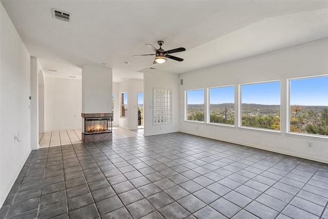 403 Rogart Dr, Spicewood, TX 78669 - unfurnished living room with a multi sided fireplace, visible vents, baseboards, a ceiling fan, and tile patterned flooring