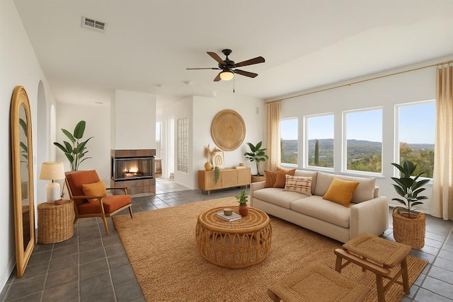 403 Rogart Dr, Spicewood, TX 78669 - living room featuring a tile fireplace, a ceiling fan, visible vents, and dark tile patterned floors