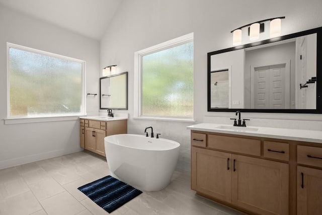 6701 Adventures Pl, Jonestown, TX 78645 - bathroom with a sink, a healthy amount of sunlight, vaulted ceiling, a soaking tub, and two vanities