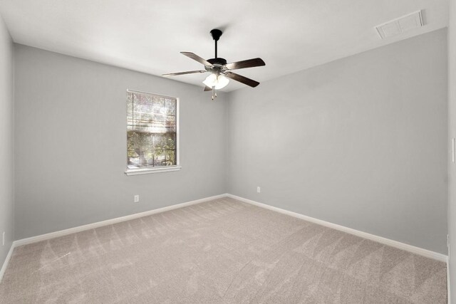 carpeted empty room featuring baseboards, a ceiling fan, and visible vents