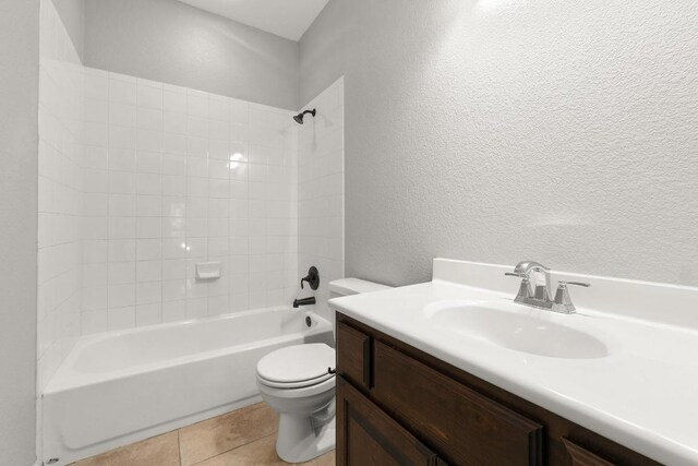 bathroom with a textured wall, vanity, toilet, tile patterned floors, and  shower combination