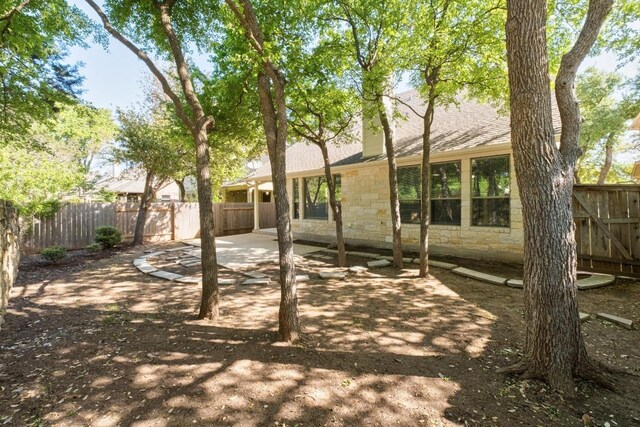 back of property featuring a fenced backyard, stone siding, and a patio area