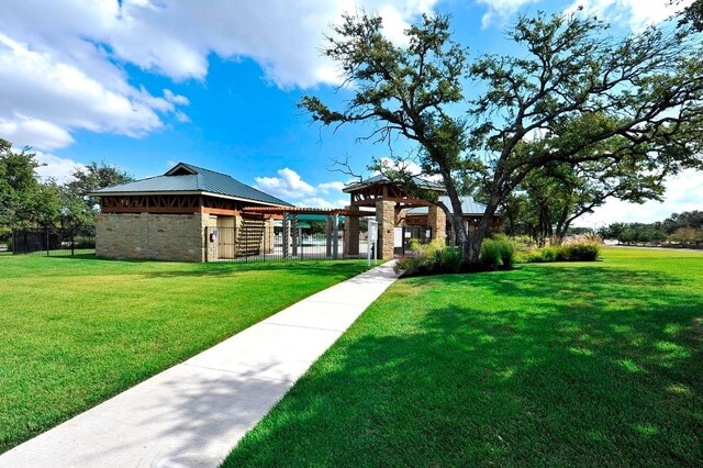 exterior space featuring fence, a front yard, stone siding, metal roof, and a gazebo