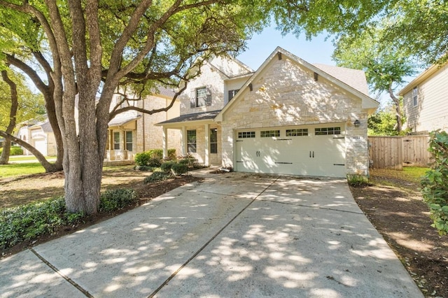 traditional-style home featuring concrete driveway, fence, stone siding, and a garage