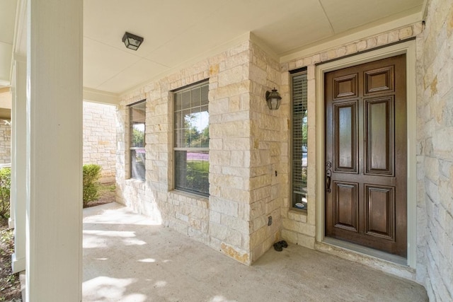 view of exterior entry featuring a porch and stone siding