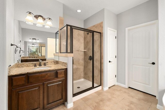 full bathroom featuring vanity, tile patterned floors, baseboards, and a stall shower