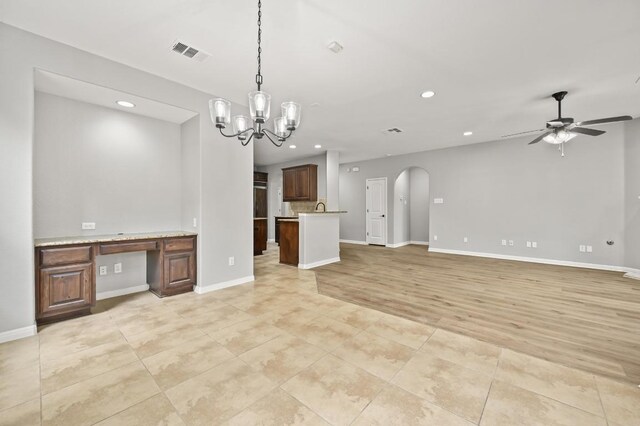 unfurnished living room featuring arched walkways, ceiling fan with notable chandelier, recessed lighting, and visible vents