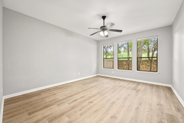 spare room with baseboards, light wood-style floors, and ceiling fan