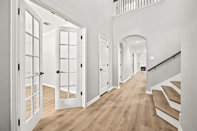 corridor with light wood-style floors, arched walkways, and baseboards
