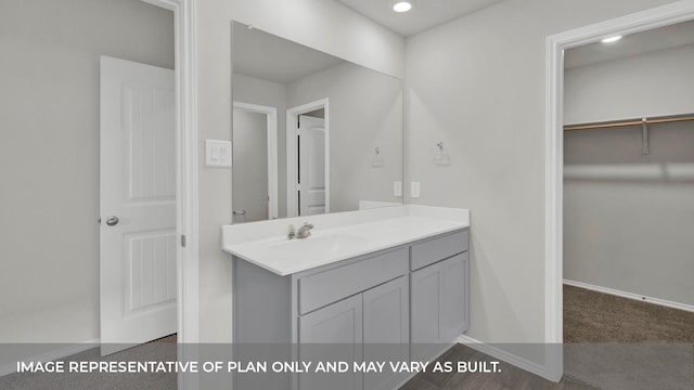 bathroom featuring recessed lighting, a walk in closet, vanity, and baseboards