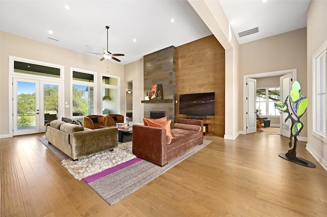 607 Flint Ridge Trl, Georgetown, TX 78628 - living area featuring light wood-type flooring, a towering ceiling, a large fireplace, a ceiling fan, and visible vents