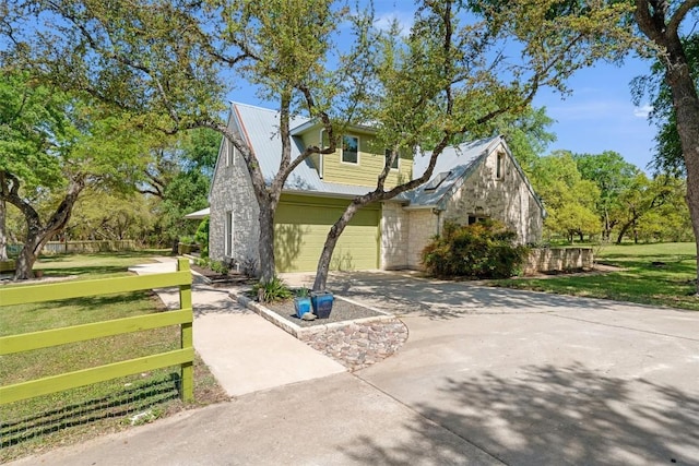 view of home's exterior featuring driveway, stone siding, and a garage