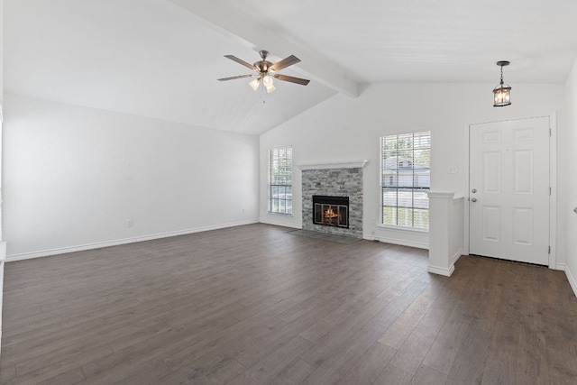 11500 Ruffed Grouse Dr, Austin, TX 78758 - unfurnished living room featuring beam ceiling, dark wood finished floors, a ceiling fan, a stone fireplace, and baseboards