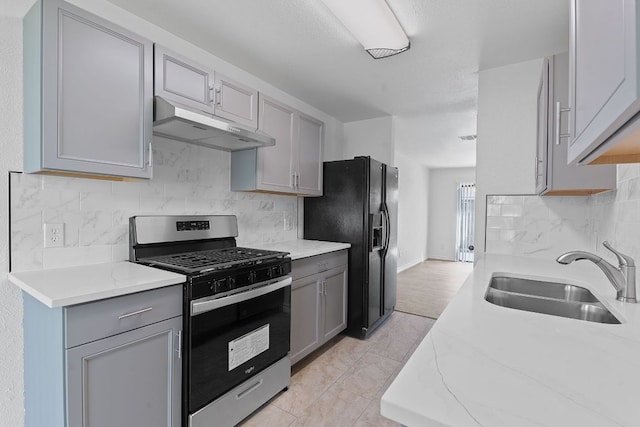 11500 Ruffed Grouse Dr, Austin, TX 78758 - kitchen featuring stainless steel gas range, under cabinet range hood, a sink, and gray cabinetry