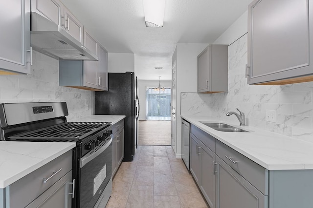 11500 Ruffed Grouse Dr, Austin, TX 78758 - kitchen with appliances with stainless steel finishes, gray cabinetry, exhaust hood, a sink, and tasteful backsplash
