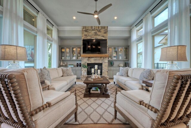 living room with ornamental molding, ceiling fan, and a brick fireplace