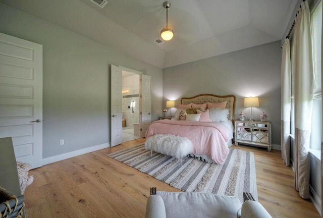 bedroom with visible vents, baseboards, light wood finished floors, and ensuite bathroom