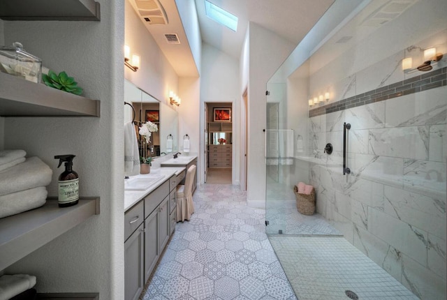 bathroom with tiled shower, vanity, and visible vents