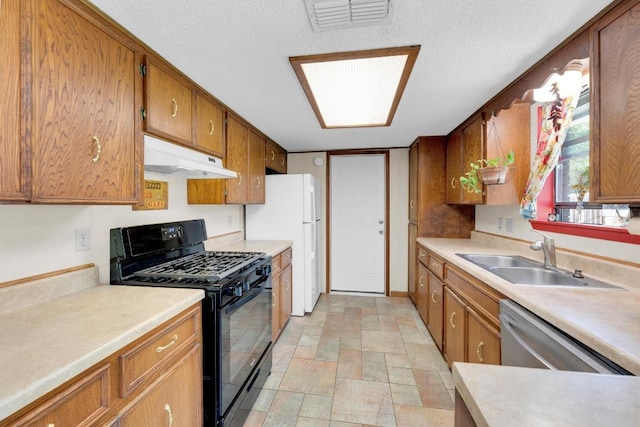 2600 Donna Dr, Taylor, TX 76574 - kitchen with gas stove, under cabinet range hood, a sink, brown cabinetry, and a textured ceiling