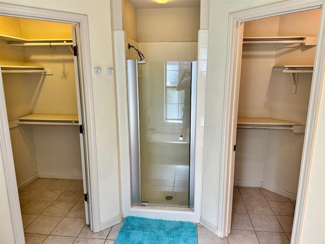 full bath featuring tile patterned flooring, baseboards, and a stall shower