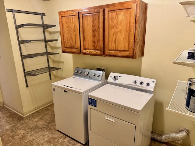 washroom featuring cabinet space, washer and clothes dryer, and baseboards