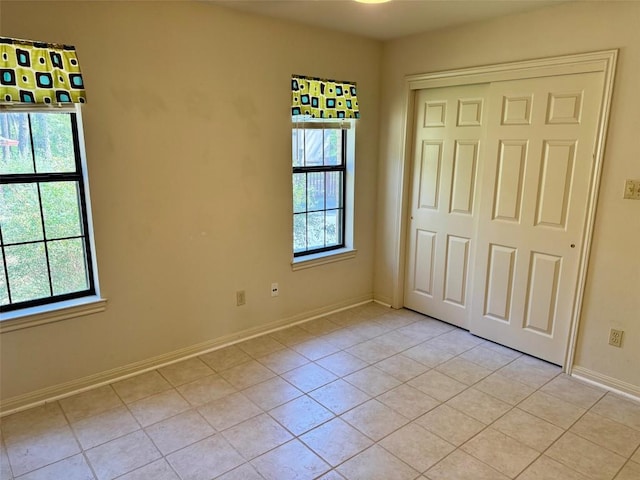unfurnished bedroom with a closet, light tile patterned flooring, and baseboards
