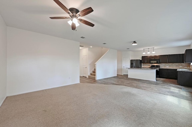 234 Coleto Creek Loop, Kyle, TX 78640 - unfurnished living room with light colored carpet, a sink, stairway, ceiling fan, and baseboards