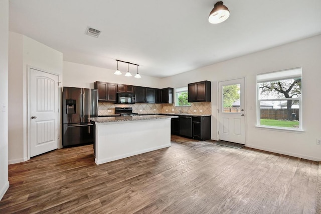 234 Coleto Creek Loop, Kyle, TX 78640 - kitchen with stainless steel refrigerator with ice dispenser, black microwave, range, backsplash, and dark wood finished floors