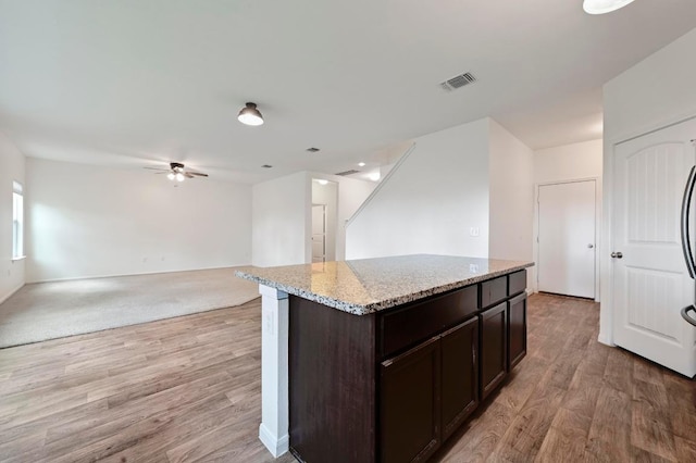 234 Coleto Creek Loop, Kyle, TX 78640 - kitchen featuring a ceiling fan, light wood-style floors, dark brown cabinetry, light stone countertops, and open floor plan