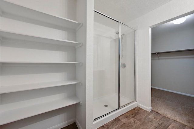 234 Coleto Creek Loop, Kyle, TX 78640 - full bathroom with a shower stall, a walk in closet, wood finished floors, and baseboards