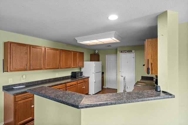 kitchen featuring stainless steel microwave, dark countertops, stove, and freestanding refrigerator