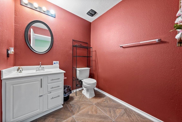half bathroom featuring a textured wall, toilet, vanity, and baseboards