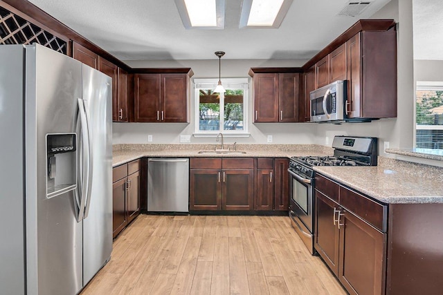 15811 De Peer Cv, Austin, TX 78717 - kitchen with appliances with stainless steel finishes, light wood-style flooring, dark brown cabinets, and pendant lighting
