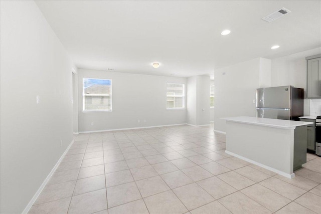 252 Fabion St, Kyle, TX 78640 - unfurnished living room with light tile patterned floors, baseboards, and recessed lighting