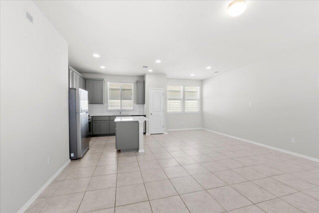 252 Fabion St, Kyle, TX 78640 - kitchen with freestanding refrigerator, gray cabinets, a kitchen island, baseboards, and light countertops
