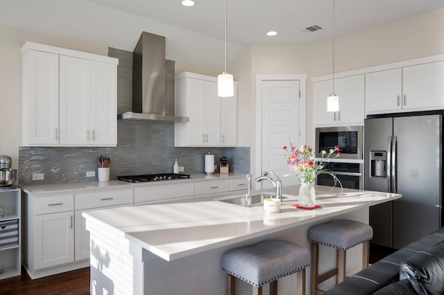344 Pisa Ln, Georgetown, TX 78628 - kitchen with wall chimney range hood, stainless steel appliances, a sink, a breakfast bar area, and backsplash