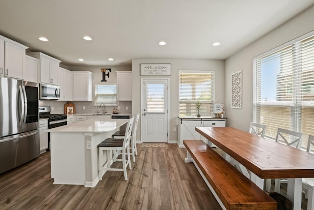 kitchen with white cabinets, dark wood-style flooring, appliances with stainless steel finishes, a sink, and backsplash