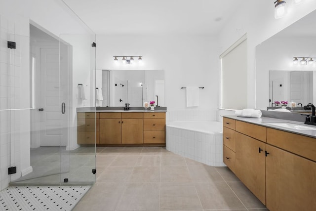 full bathroom with a shower stall, tile patterned flooring, a bath, and two vanities