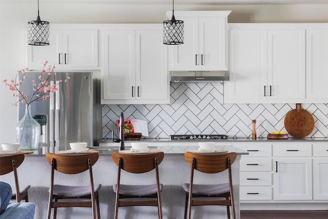 3307 Columbus Way, Round Rock, TX 78665 - kitchen featuring stainless steel appliances, under cabinet range hood, a kitchen bar, and decorative backsplash