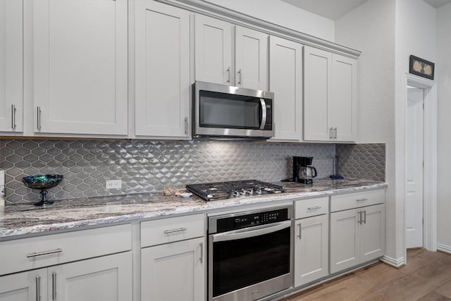728 Clear Spring Ln, Leander, TX 78641 - kitchen featuring stainless steel appliances, tasteful backsplash, light wood-style floors, and light stone countertops