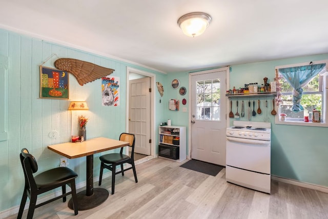 523 Ash St, Lockhart, TX 78644 - kitchen with white electric range oven, light wood finished floors, baseboards, and wooden walls