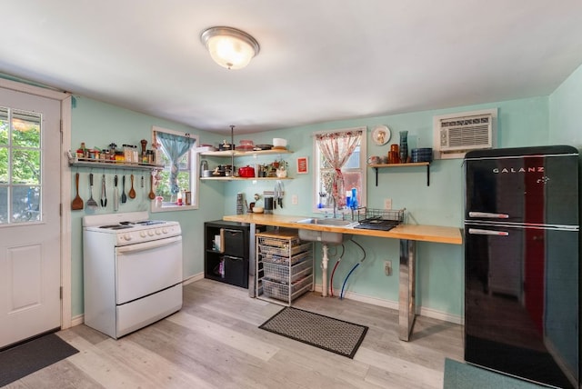 523 Ash St, Lockhart, TX 78644 - kitchen featuring freestanding refrigerator, white gas range, light wood-style flooring, open shelves, and an AC wall unit