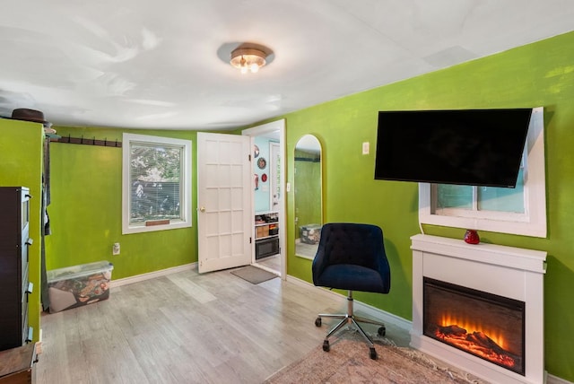 523 Ash St, Lockhart, TX 78644 - sitting room featuring arched walkways, a lit fireplace, baseboards, and wood finished floors