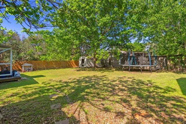523 Ash St, Lockhart, TX 78644 - view of yard with a trampoline, a storage shed, a fenced backyard, and an outdoor structure