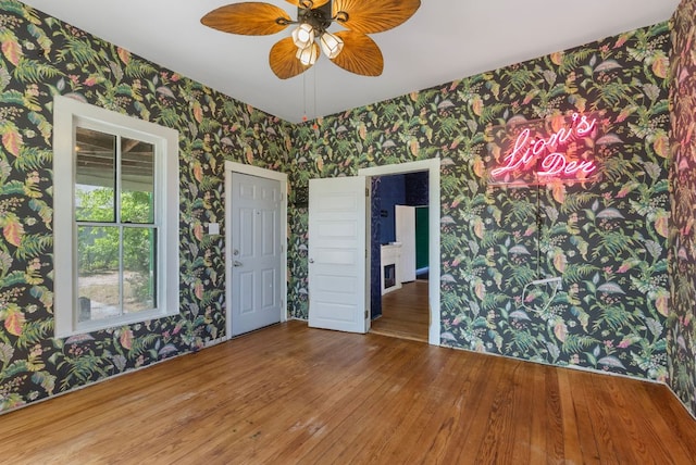 523 Ash St, Lockhart, TX 78644 - spare room with wallpapered walls, wood finished floors, and ceiling fan